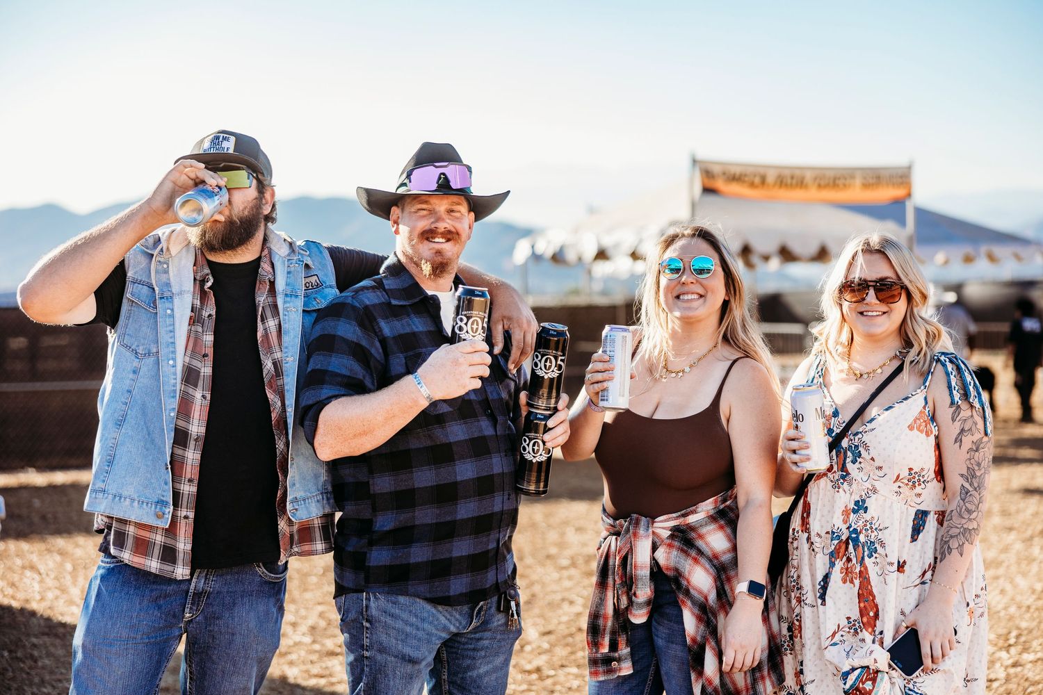 Friends enjoying drinks and conversation at outdoor country music festival.