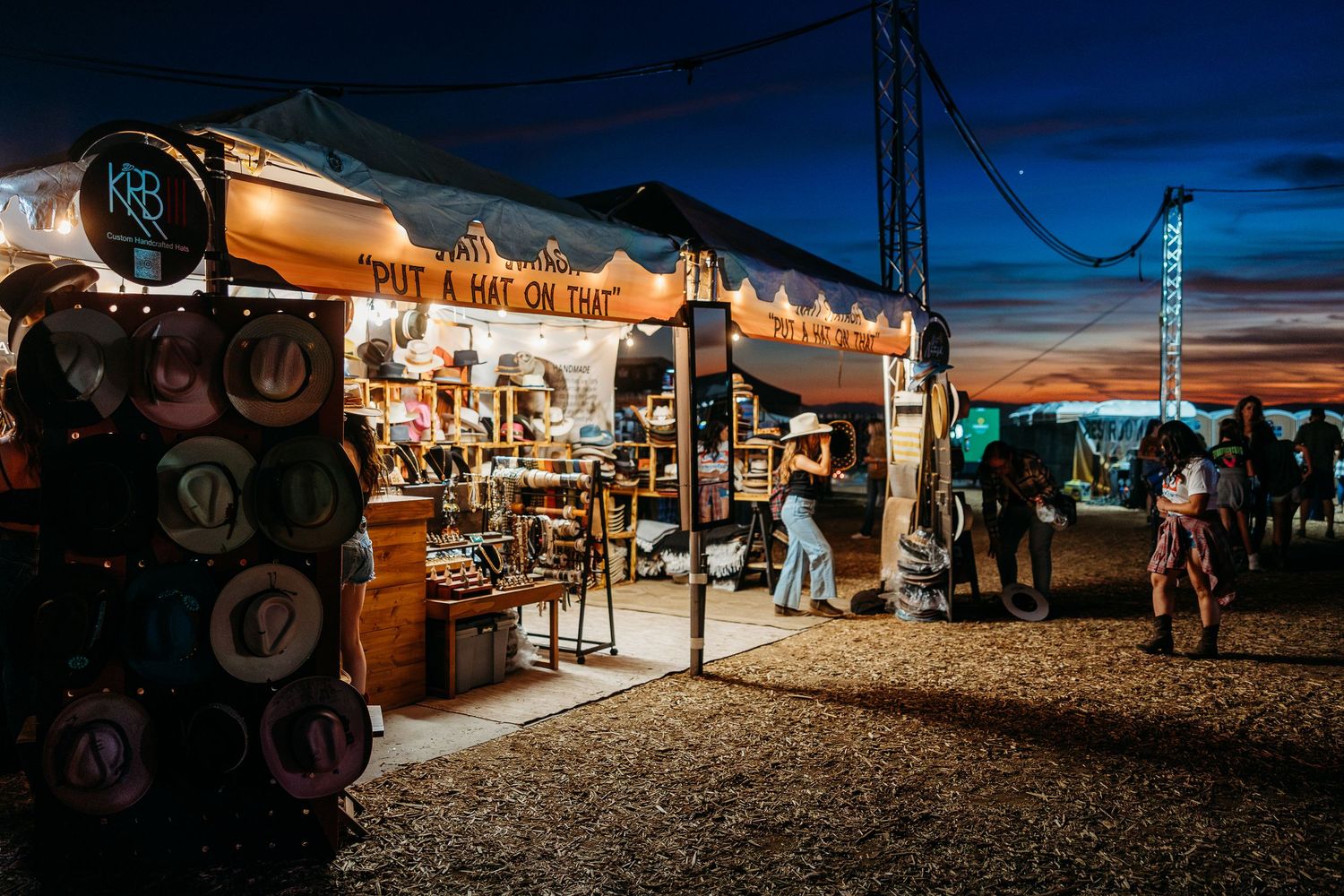 Evening market stalls with colorful lights and vendors selling merchandise at a lively outdoor bazaar.