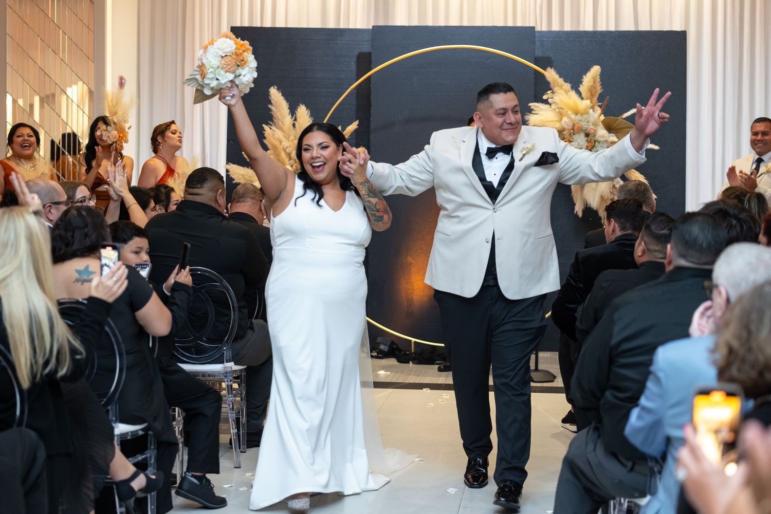 Wedding party dancing and celebrating in an elegantly decorated venue with white and gold decor.