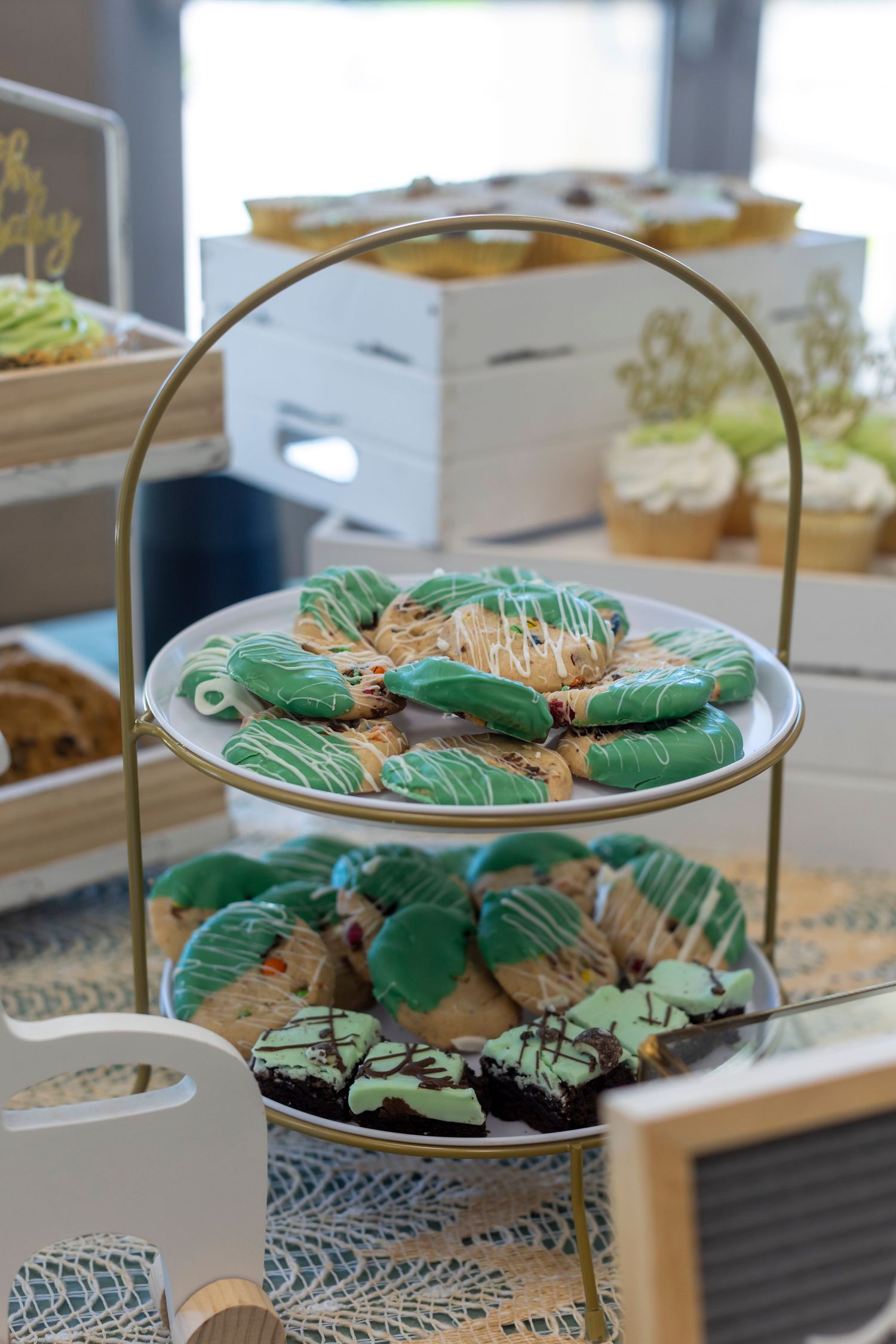 Green and gold decorated cookies displayed on tiered serving platters.