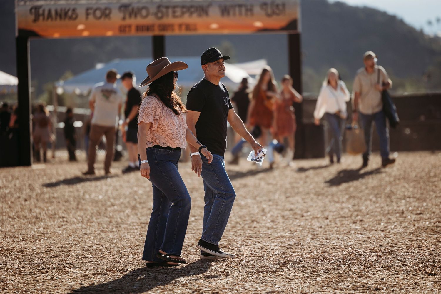 Festival attendees enjoying outdoor activities under a banner sign.