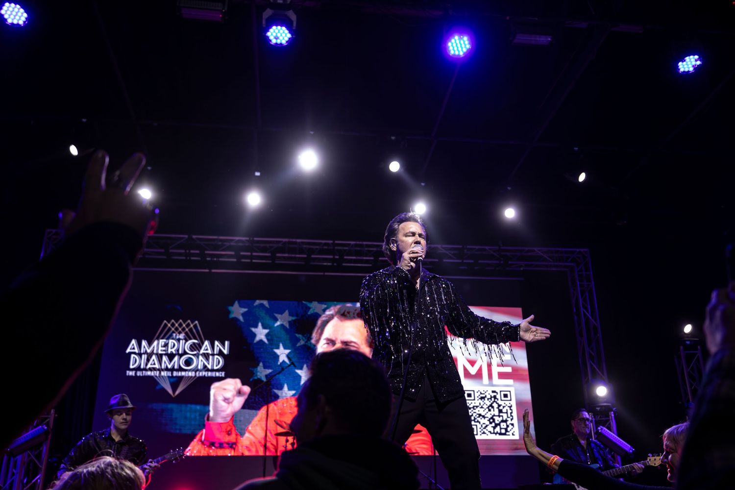 Stage performer silhouetted against bright spotlights during nighttime concert in Garden Grove.