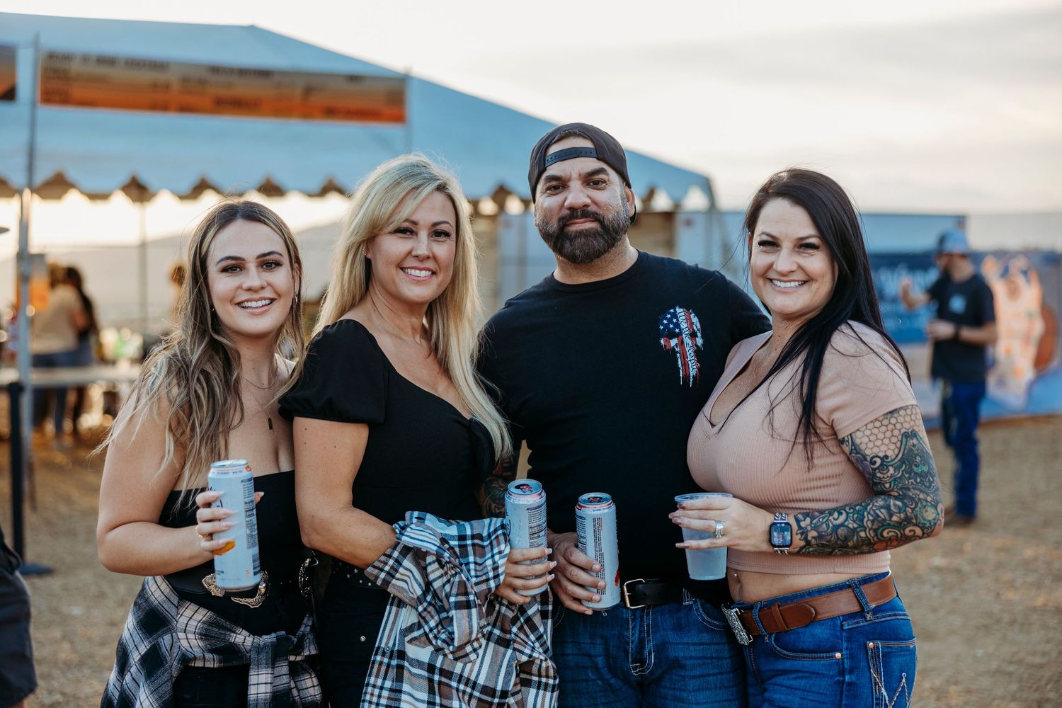 Festival attendees in western wear gathering at a country music event under blue skies.