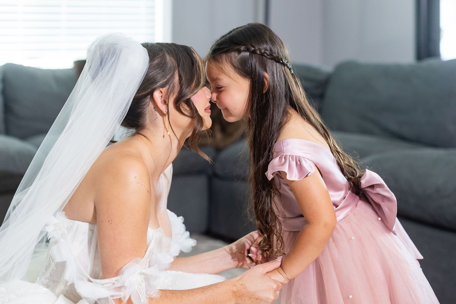 A heartwarming moment shared between a bride in her wedding dress and a young girl in pink.