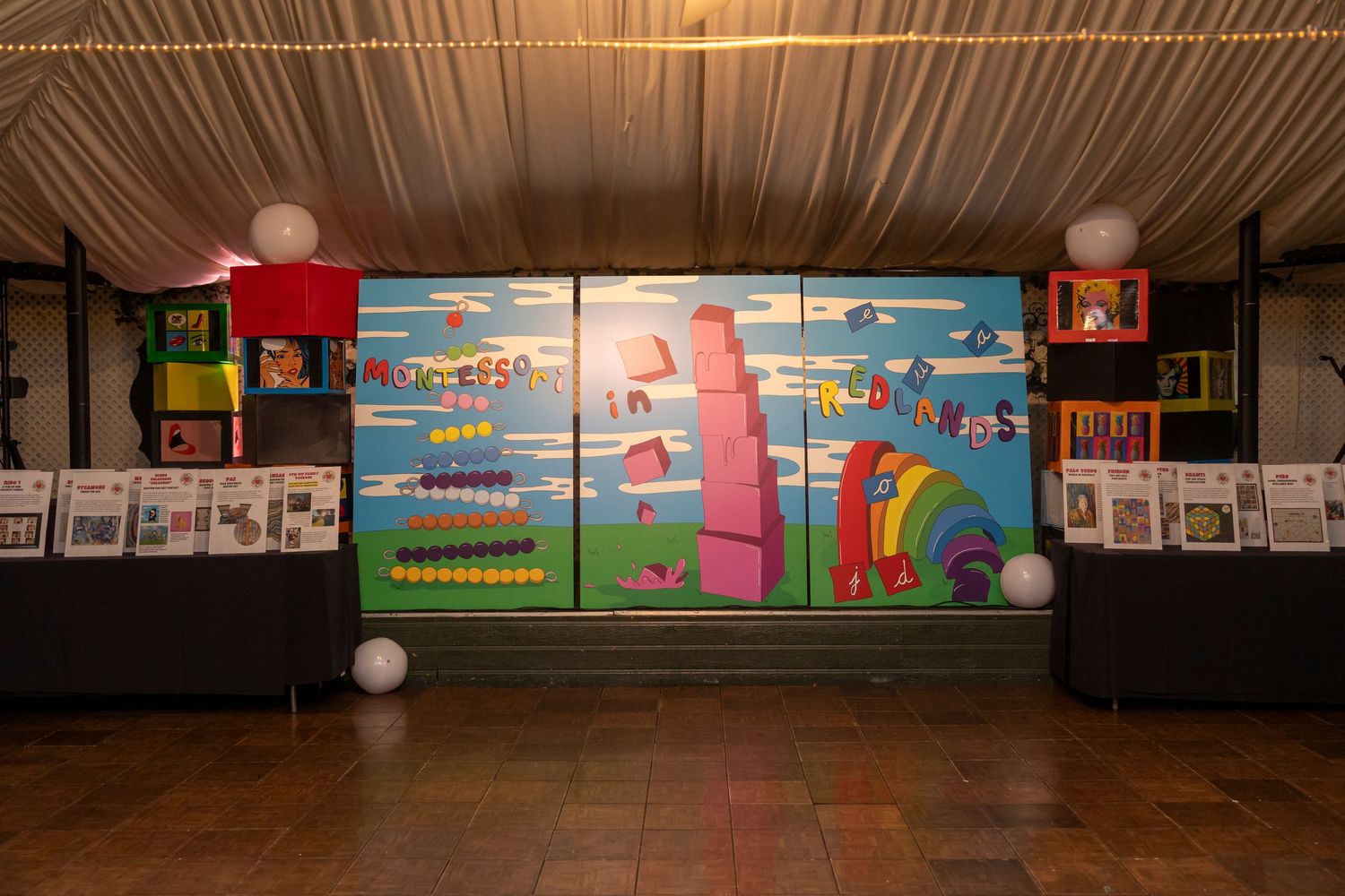 Cartoon-style decorative wall murals with bright colors in a large event space with draped ceiling.