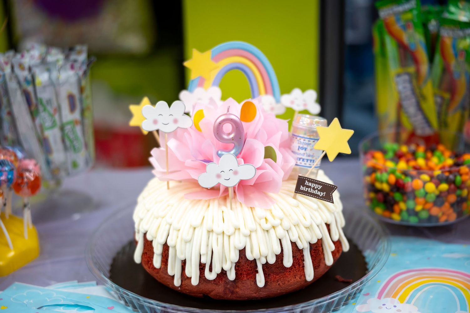 Colorful birthday cake decorated with rainbow details and star-shaped candles on display.
