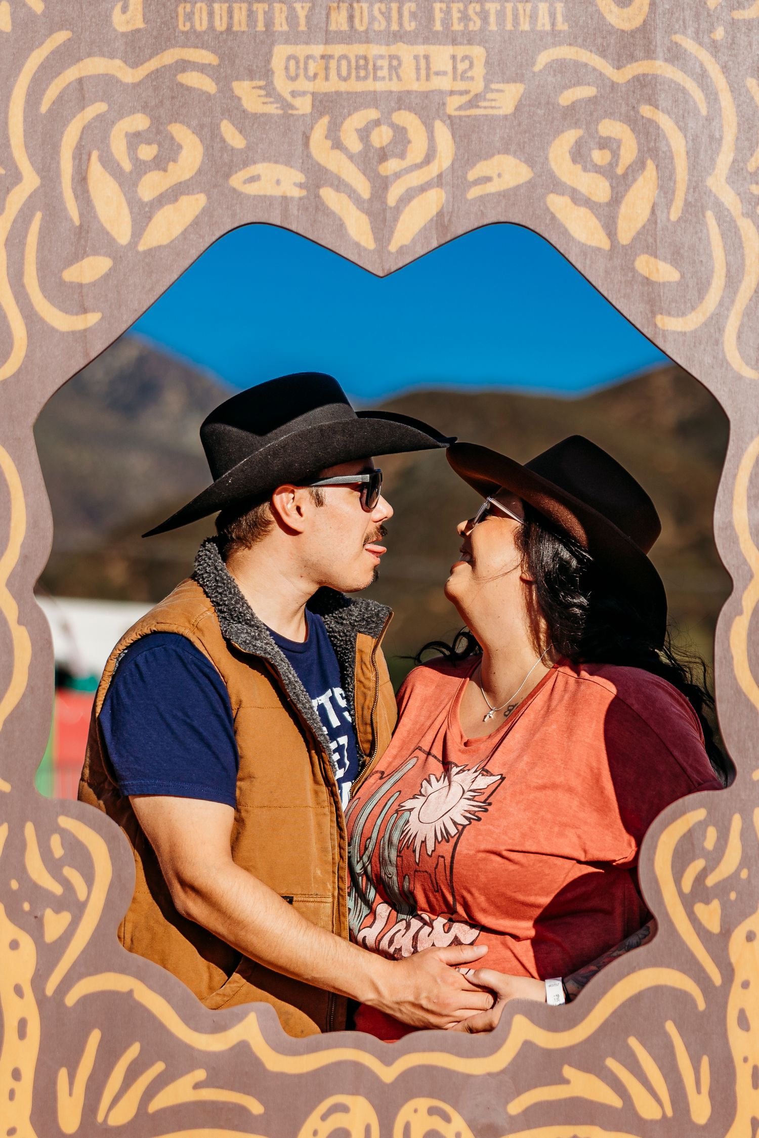Romantic couple moments captured through ornate festival photo frames at sunset.