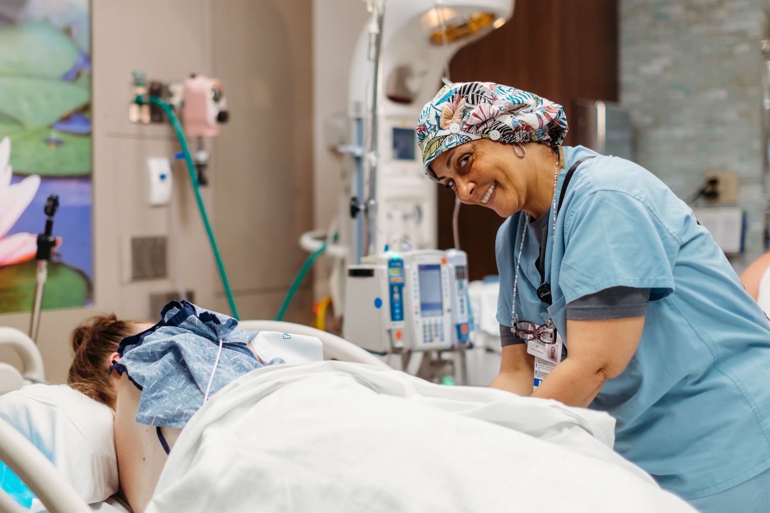 Medical staff in scrubs tend to a patient in a hospital room.