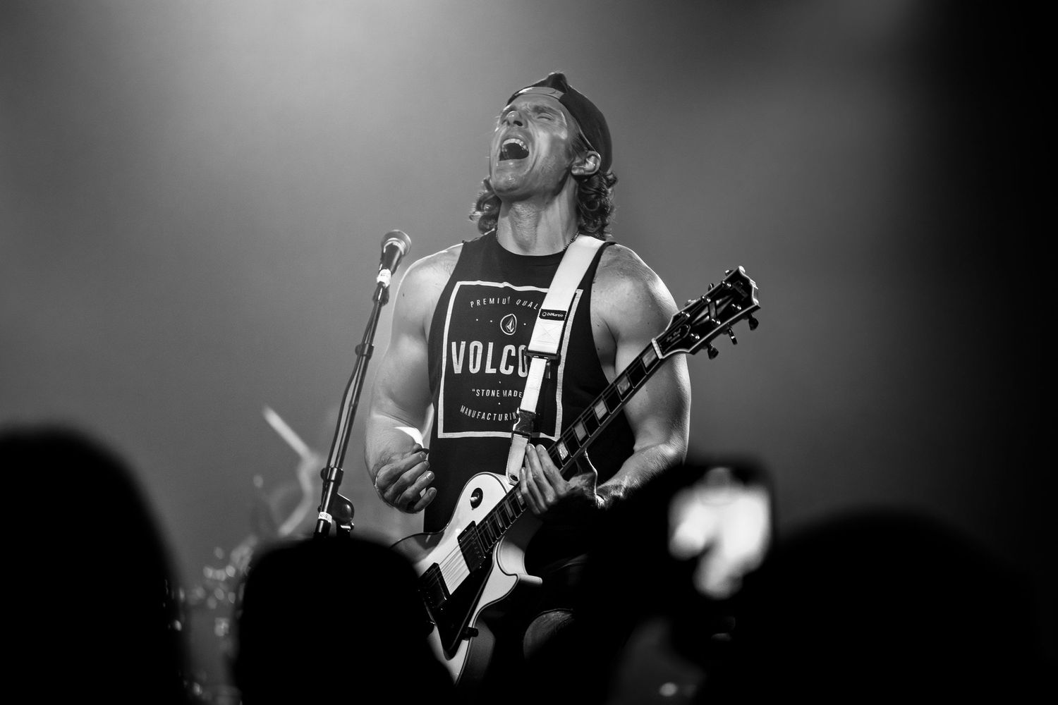 Black and white concert photo showing performer with guitar playing under dramatic stage lighting in Pomona.