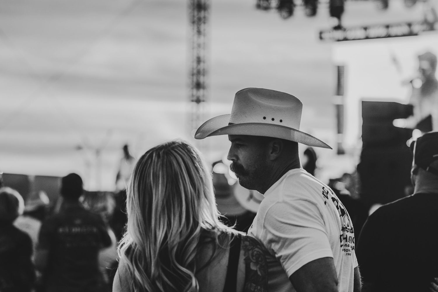 Black and white photo of concert attendees wearing cowboy hats watching a performance.