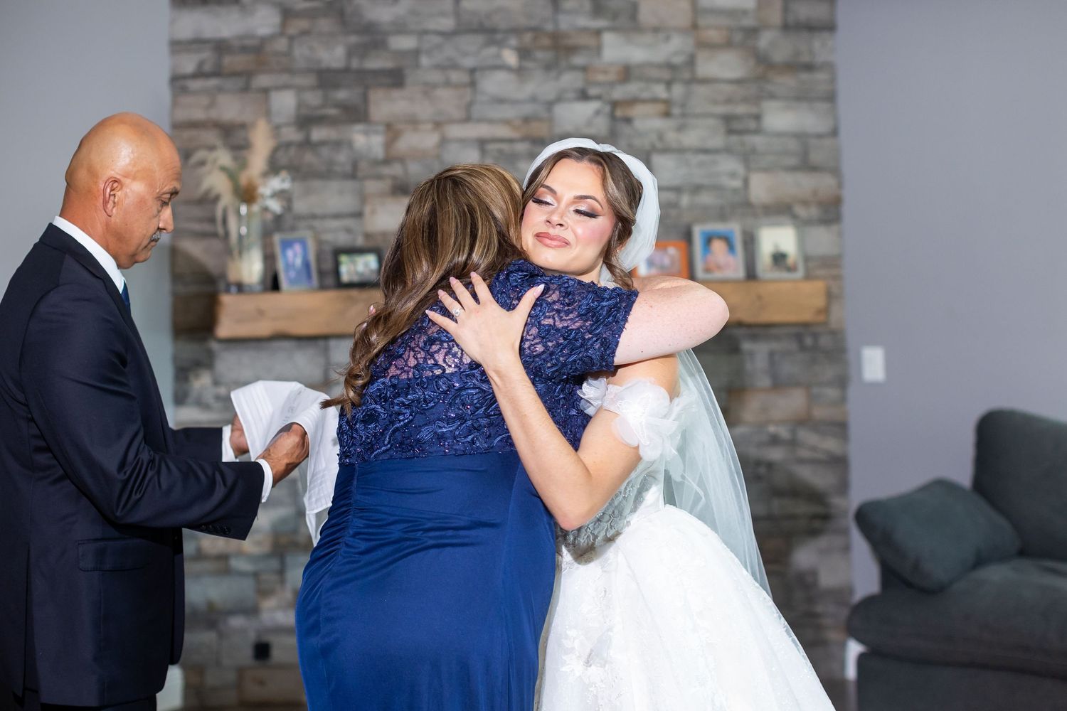An emotional embrace shared during a wedding ceremony with a stone fireplace backdrop.