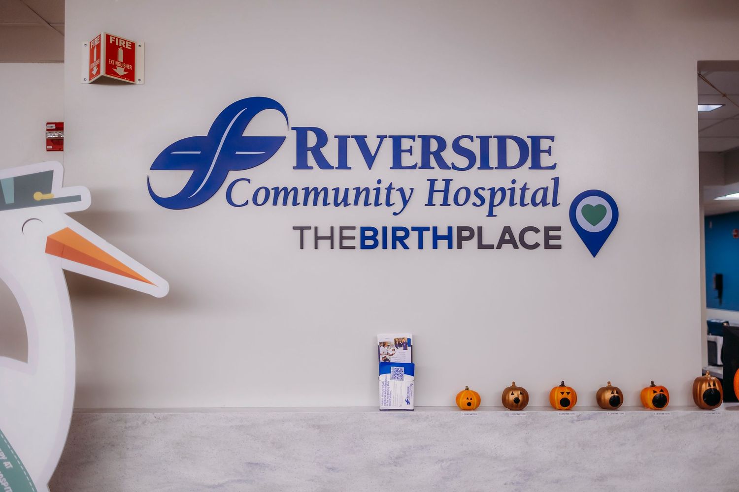 Hospital sign reading 'Riverside Community Hospital The Birthplace' with decorative elements.