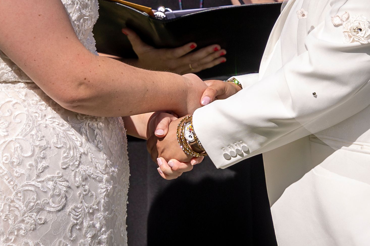 Close-up of hands clasped together during a wedding ceremony.