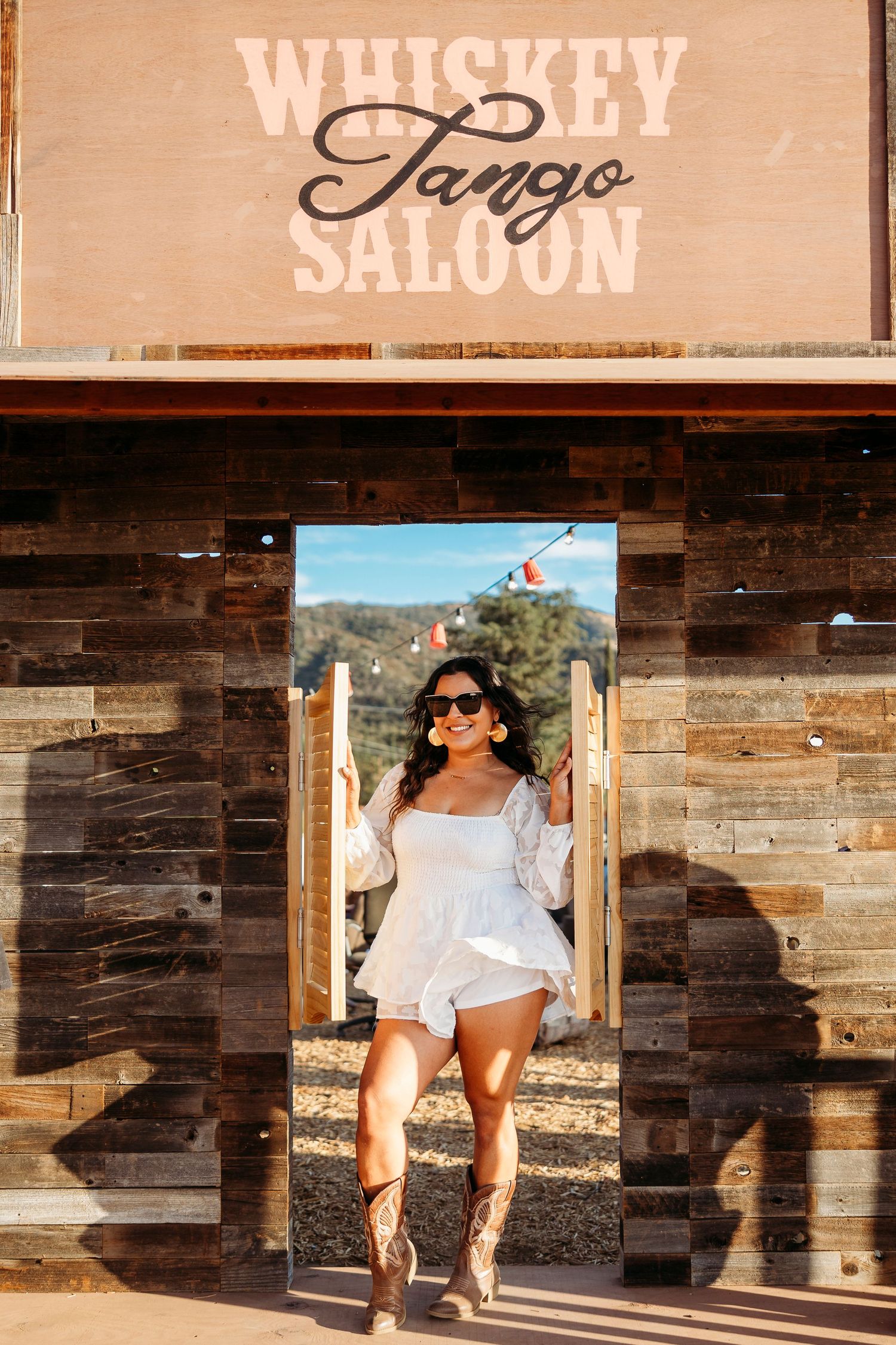 Rustic wooden facade of Whiskey Tango Saloon with person posing in white outfit at entrance.