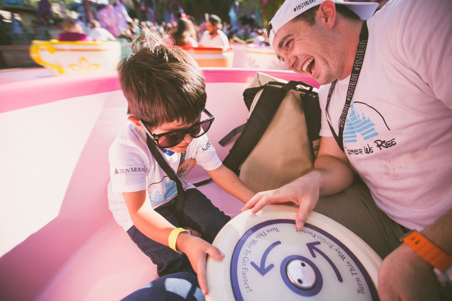 Two people examine a unique circular object together on a pink inflatable surface during a sunny outdoor event.