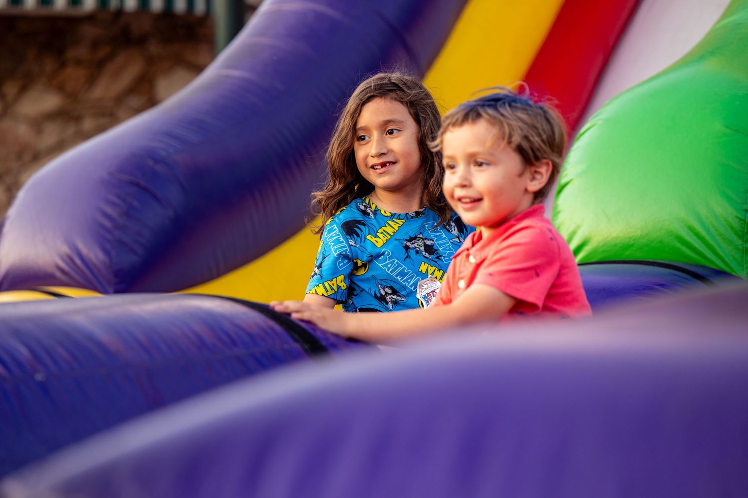 Children enjoying a colorful inflatable bounce house at an outdoor event.