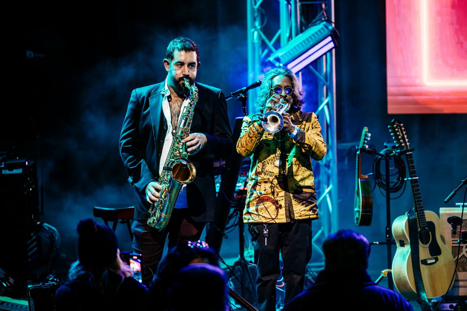 Musicians performing with saxophone and vocal microphone on illuminated stage with blue lighting in Garden Grove.