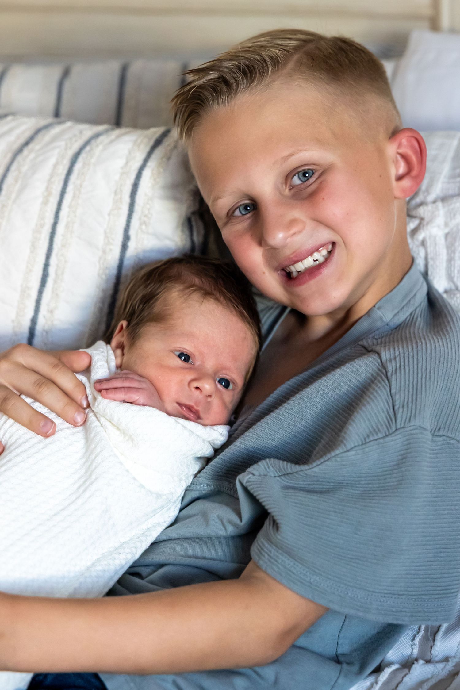Children lying together on striped bedding sharing sweet bonding moments.
