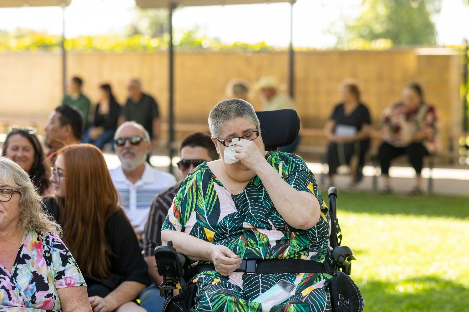 Wedding guests seated outdoors at ceremony watching emotional moment unfold.