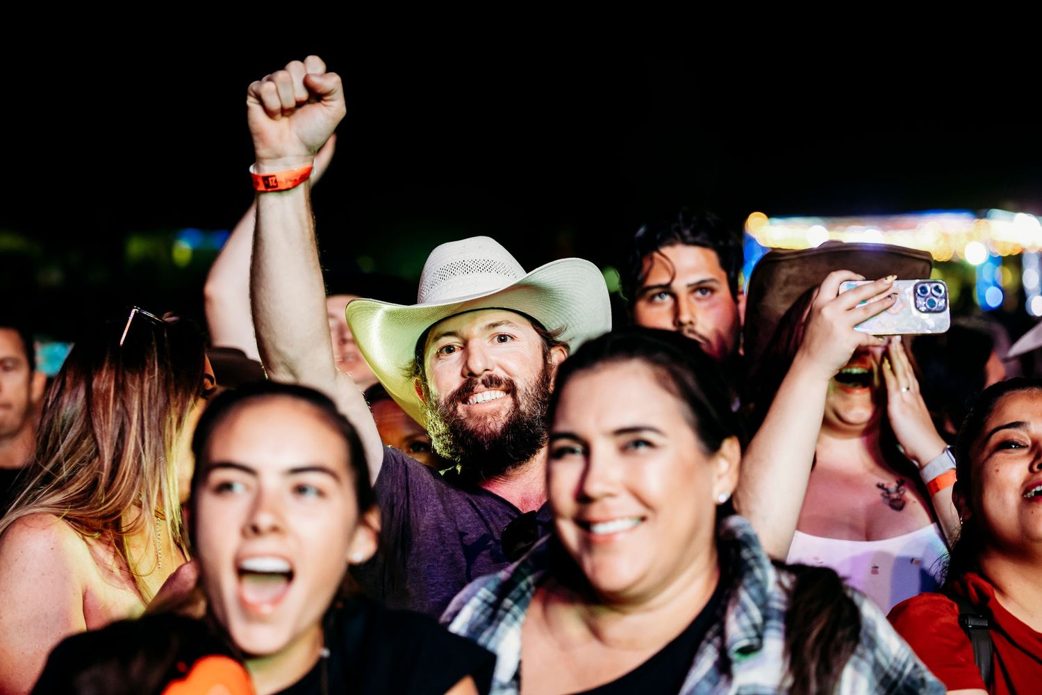Energetic crowd enjoying live music performance in a dark venue with concert lighting.