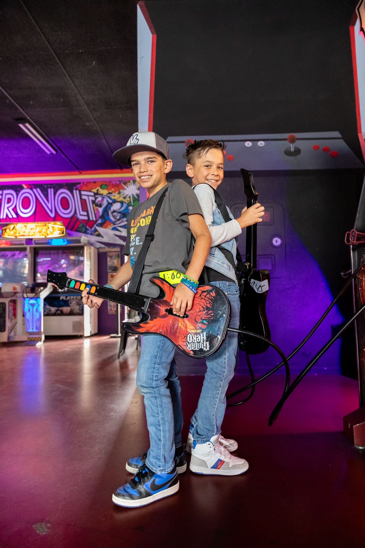 Arcade visitors enjoy gaming experience in neon-lit entertainment space.