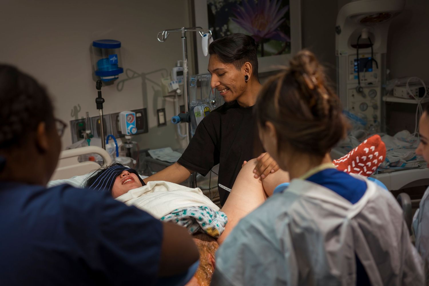 Healthcare providers gather around patient bed during labor and delivery.