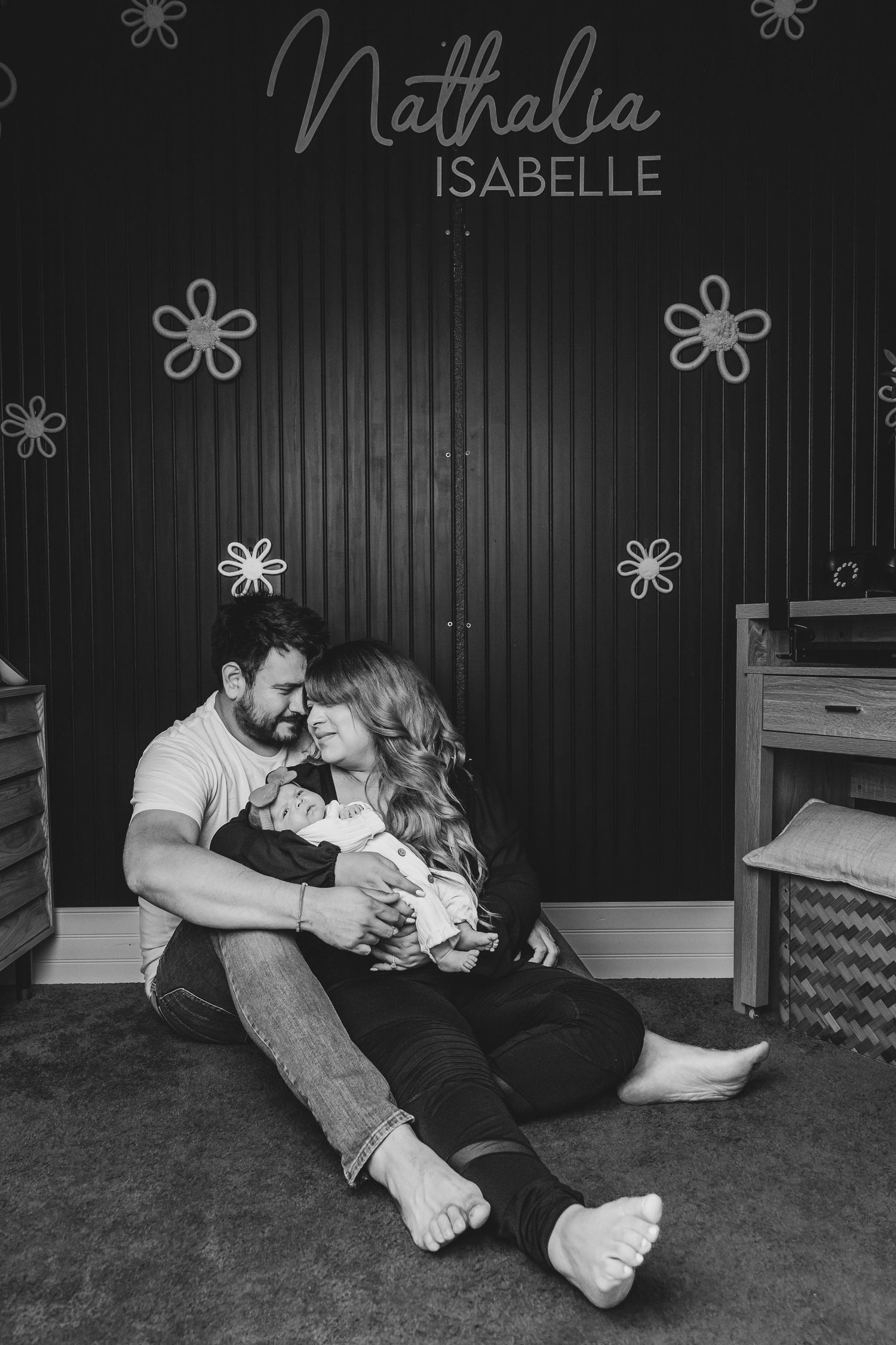Black and white portrait of tender family moment in nursery setting.
