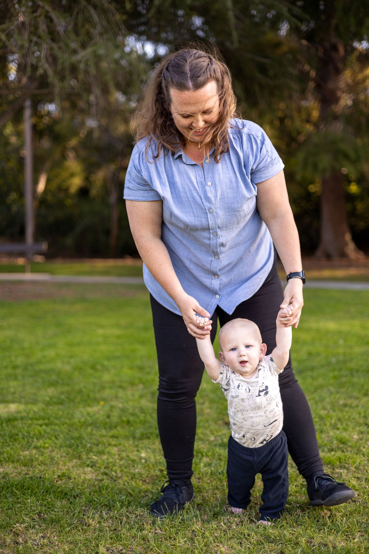 Hilary helping Lucca learn to take their first steps on grass in a Chino park.