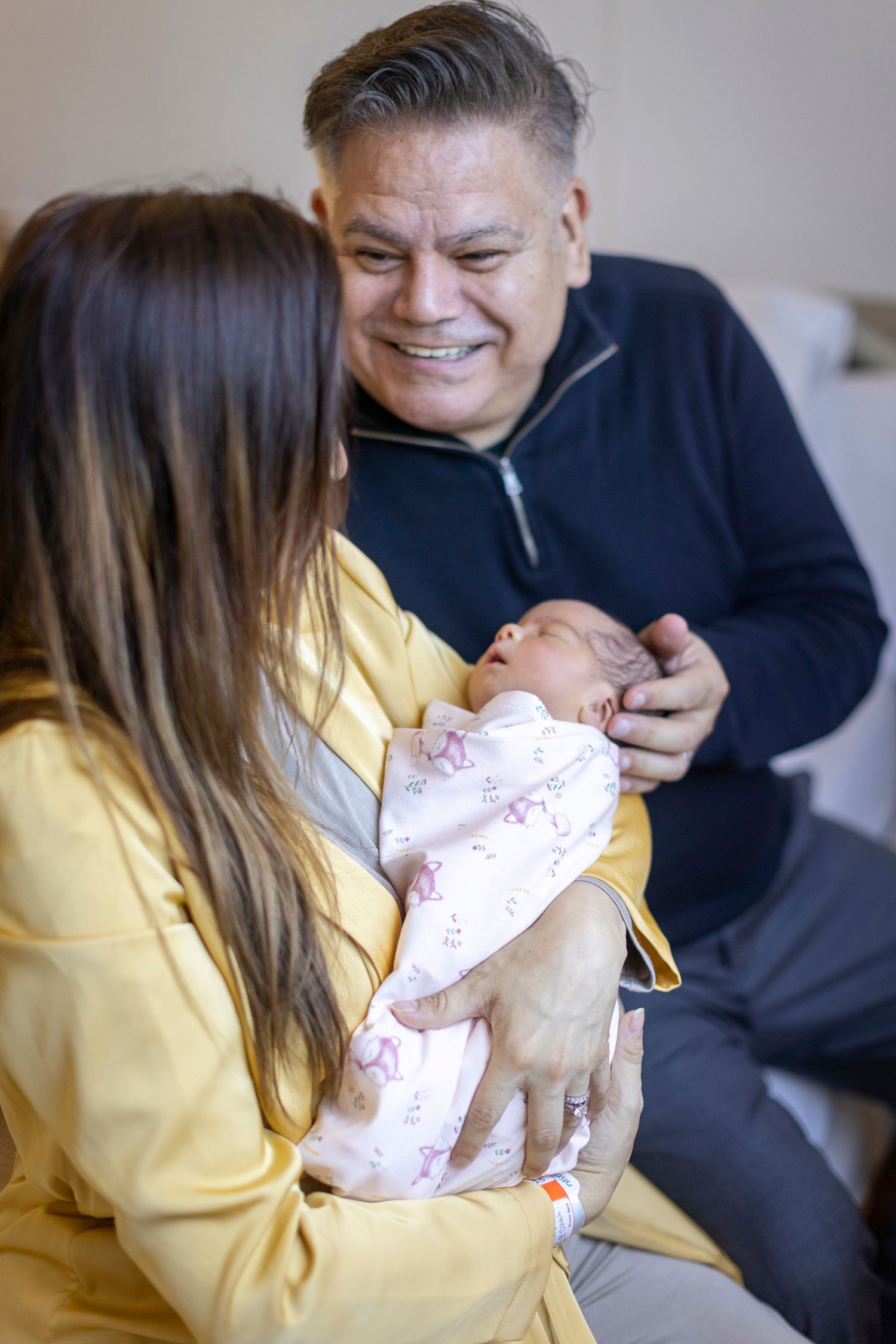 Loving family moment with newborn baby in pink outfit.