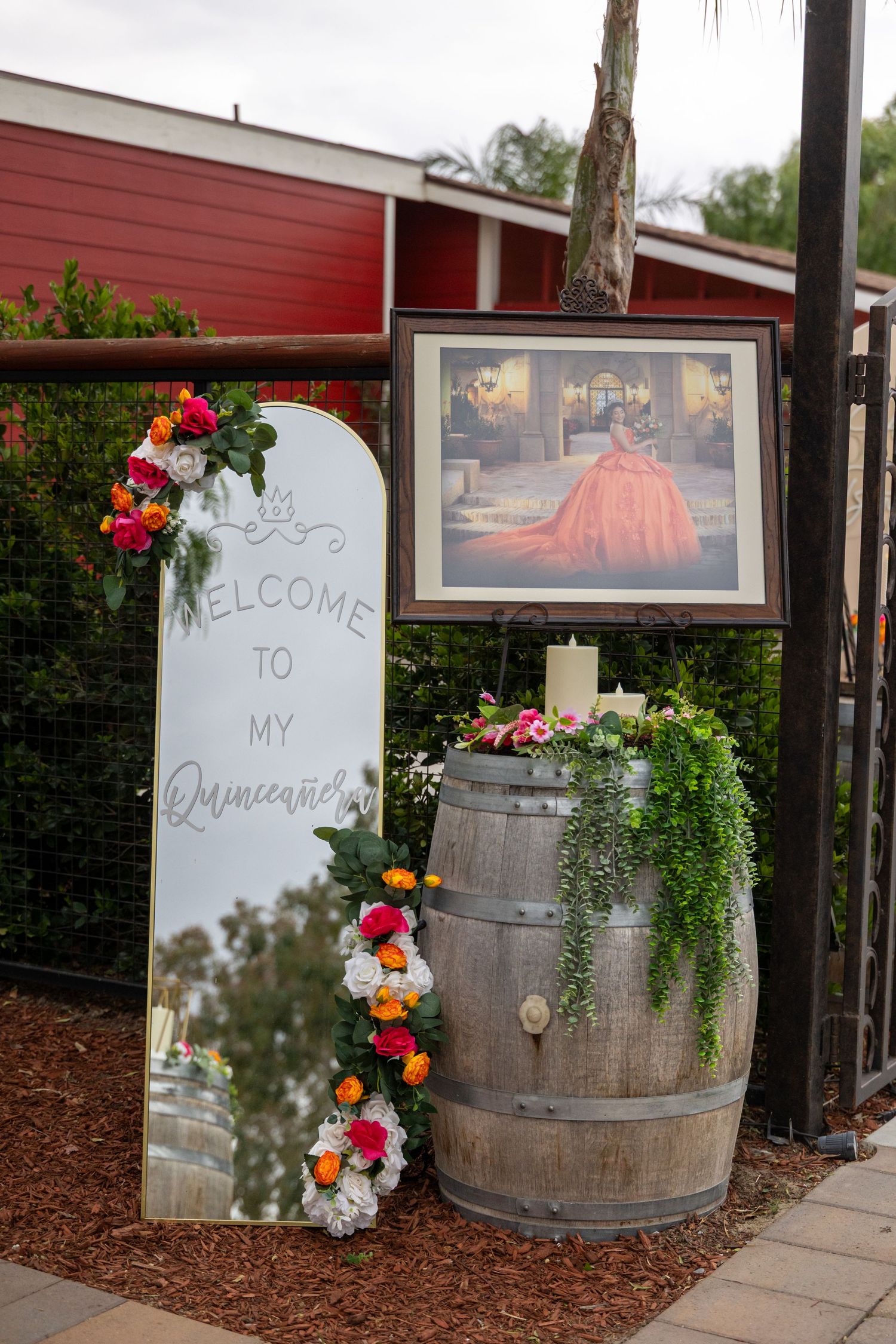 Rustic welcome display with wooden barrels and floral decorations for quinceañera celebration.