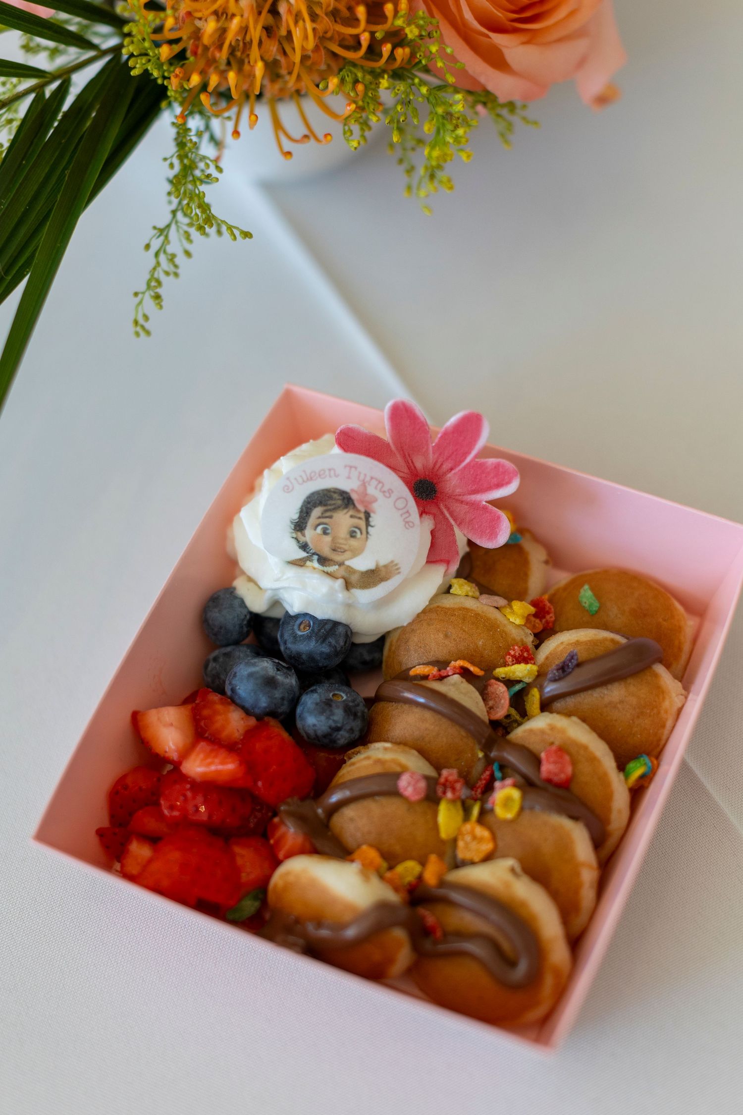Decorative food box containing colorful berries, cookies, and floral garnishes in Huntington Beach.