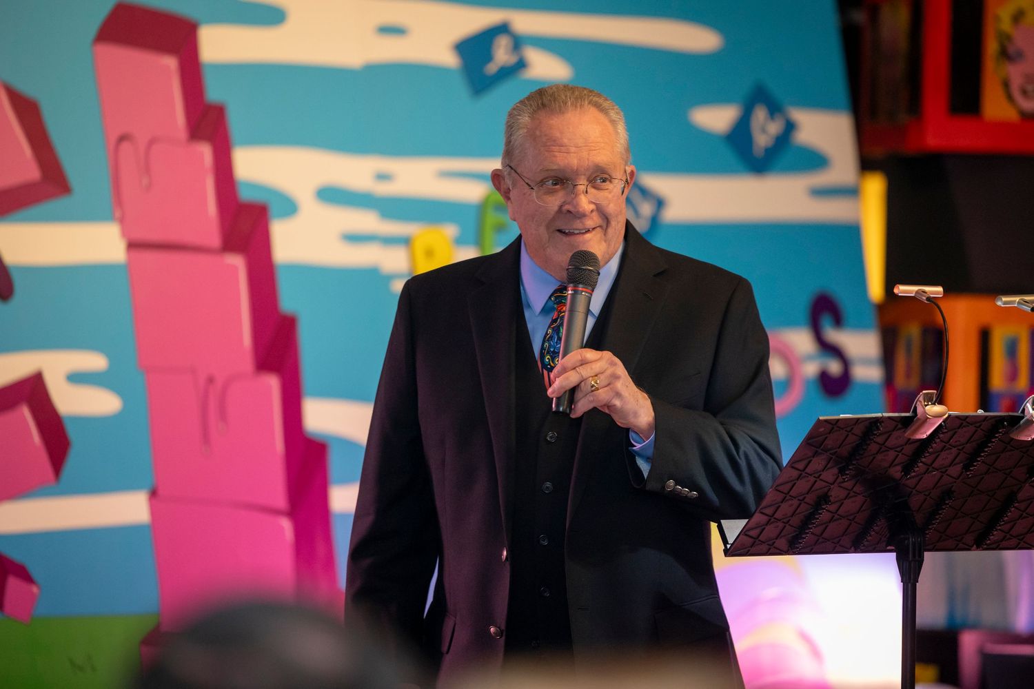 Event space with bright blue wall art featuring pink geometric shapes and cloud designs.