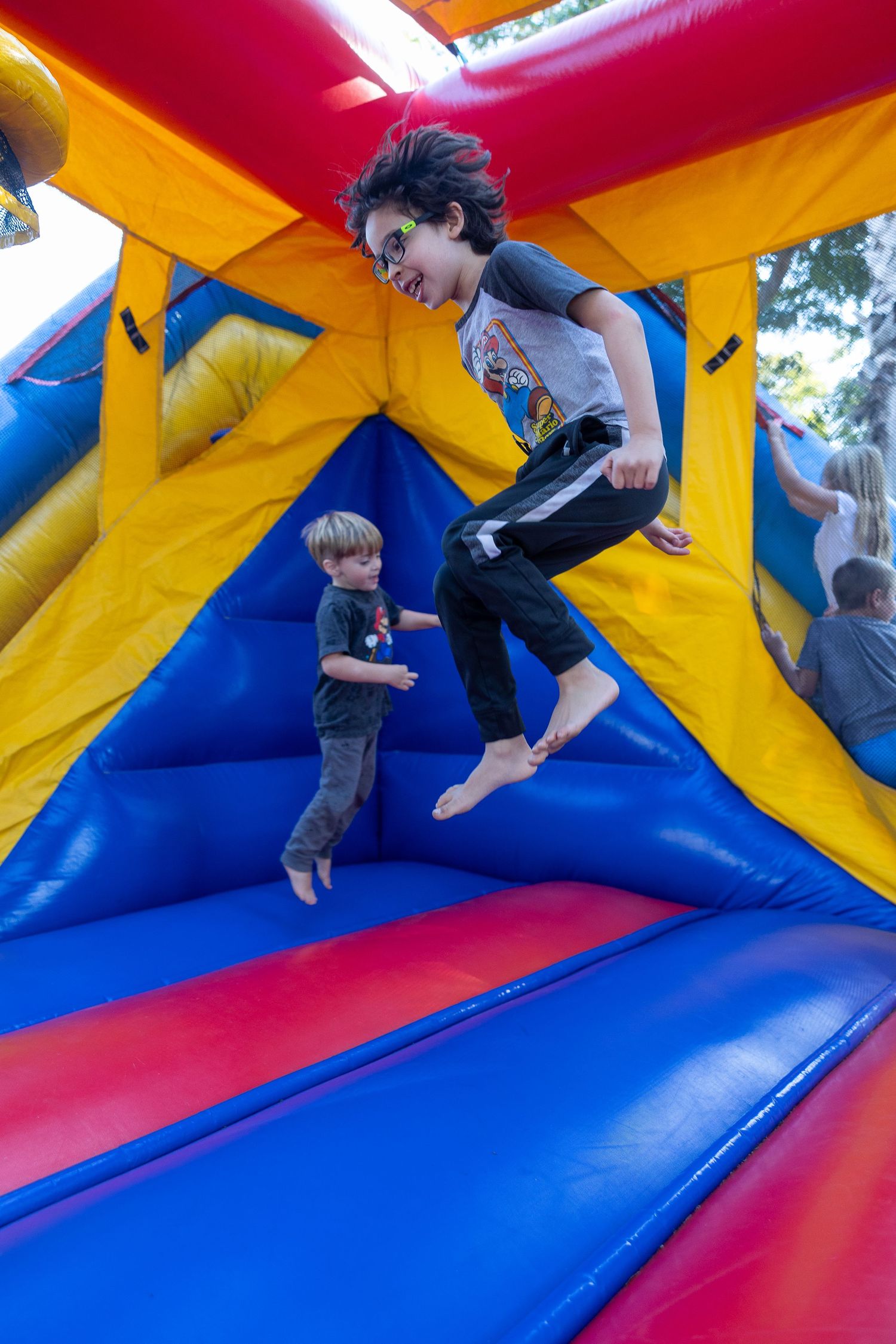 Children playing on colorful inflatable bounce house at outdoor event.
