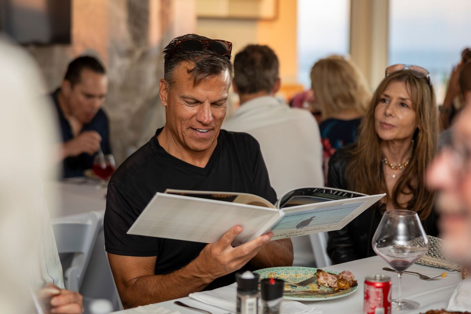 People seated at dinner tables enjoying a meal while looking at menus.