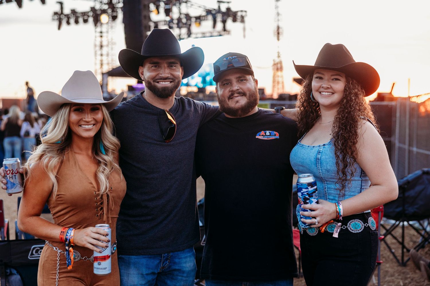 Concert goers in western attire socializing and posing together at an outdoor music event.