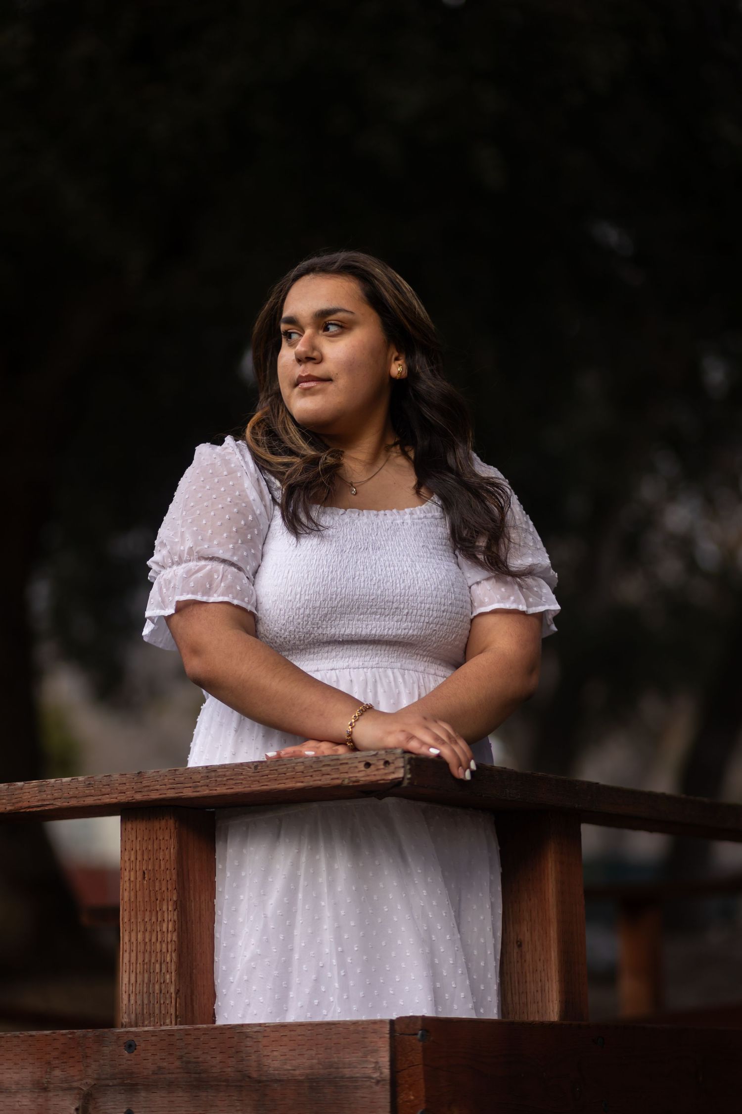 Person in white dress standing on wooden deck with moody lighting in Oak Glen.