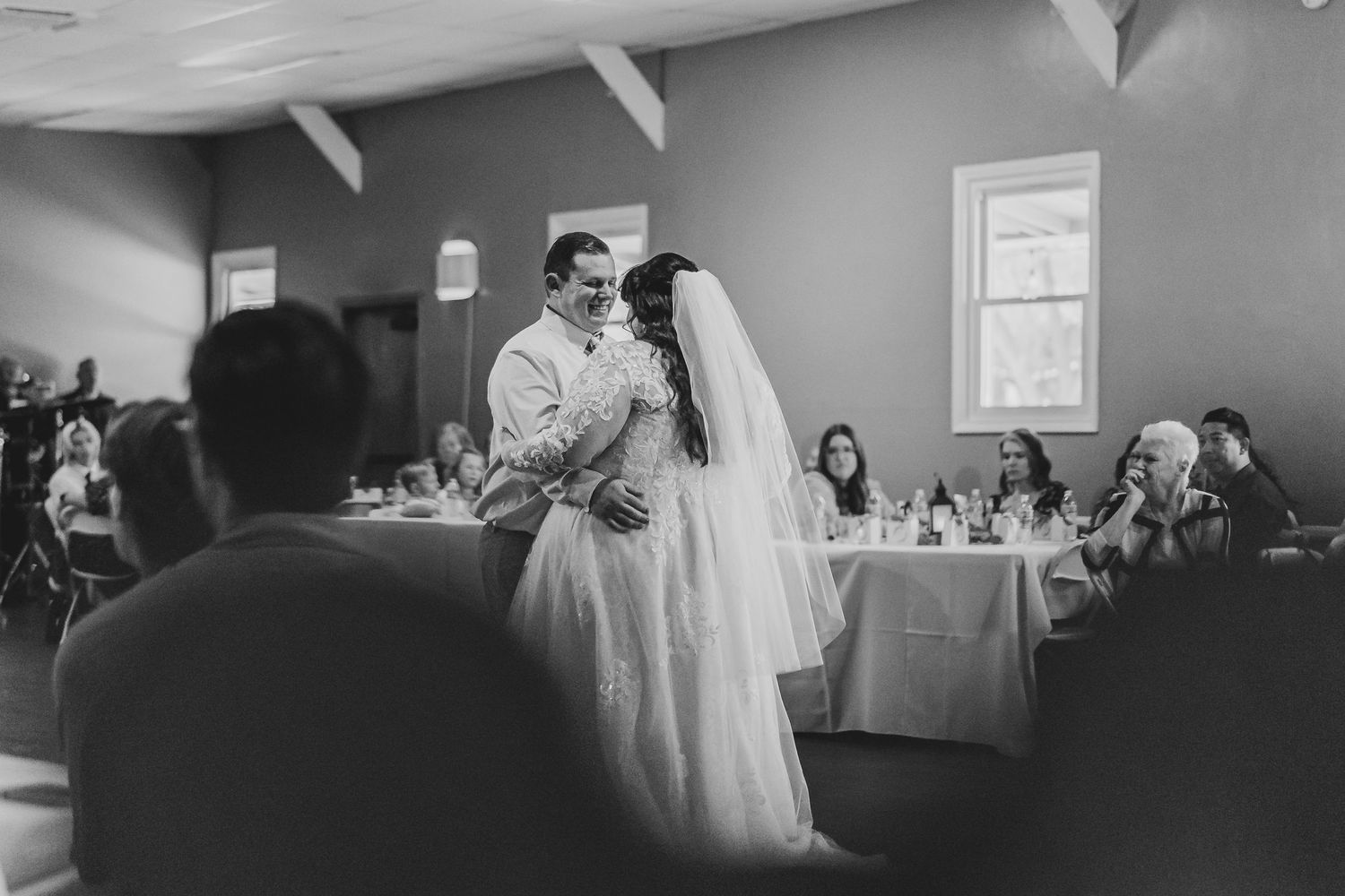 Black and white reception photo of newlyweds first dance indoors.