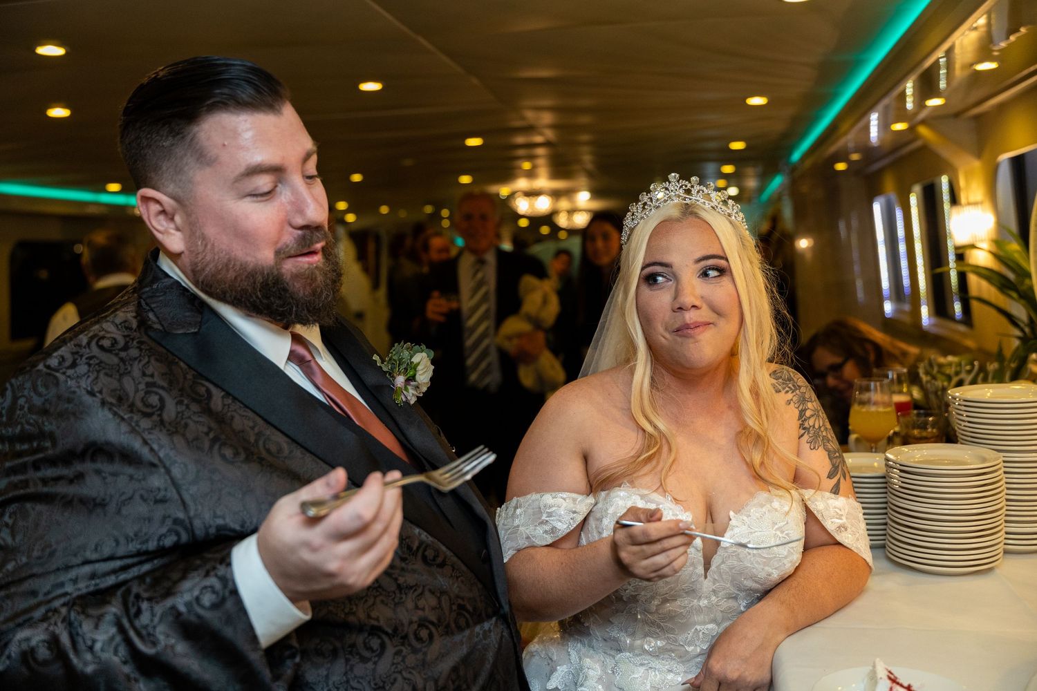 Wedding couple enjoying their reception meal in elegant venue with green lighting.