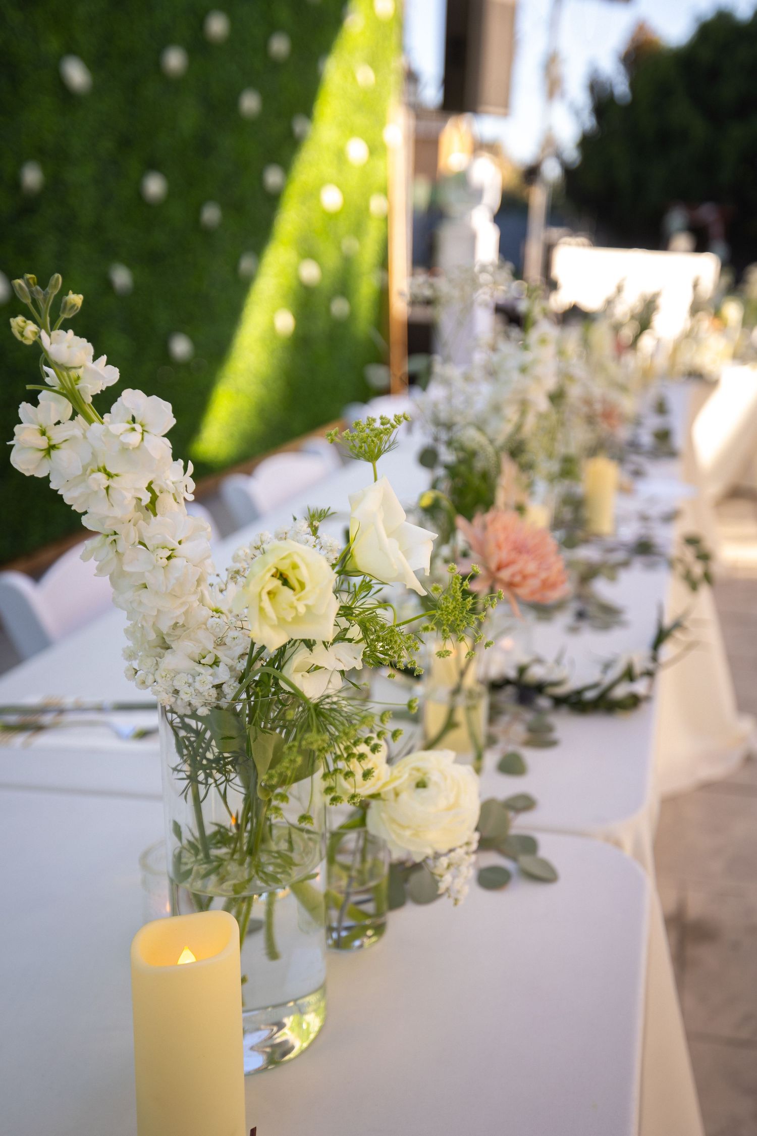 Elegant wedding table decor featuring white floral centerpieces and glowing candles.