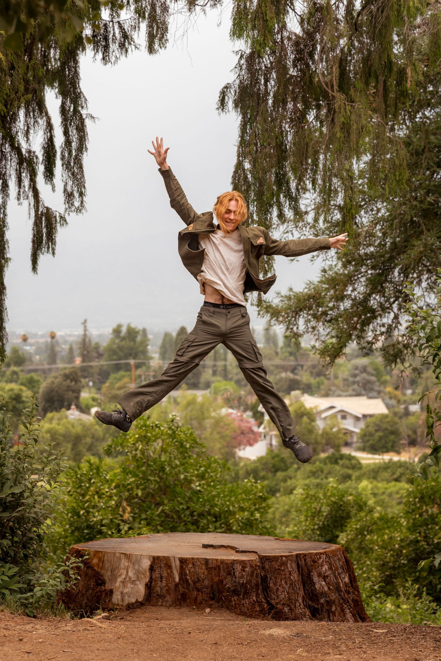 Energetic leap captured mid-air above a tree stump in an outdoor setting in Redlands.