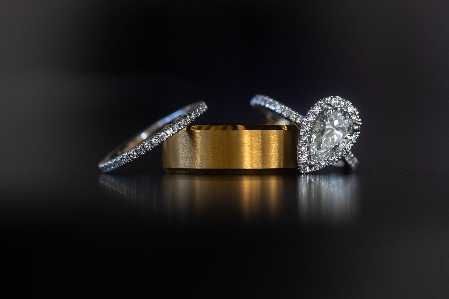 Wedding rings and jewelry photographed on dark background with dramatic lighting.