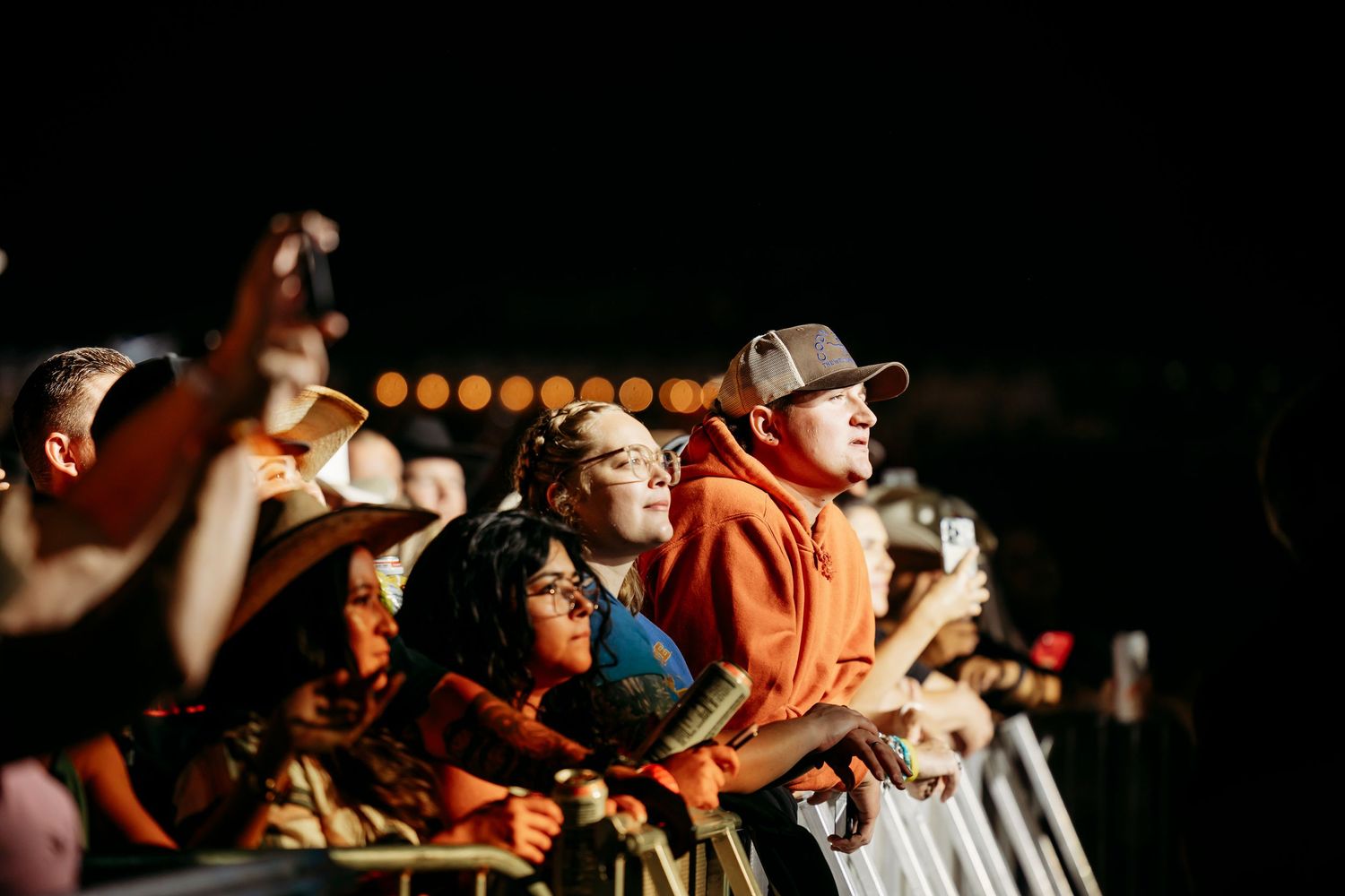Enthusiastic crowd watching and cheering during a darkened concert performance.