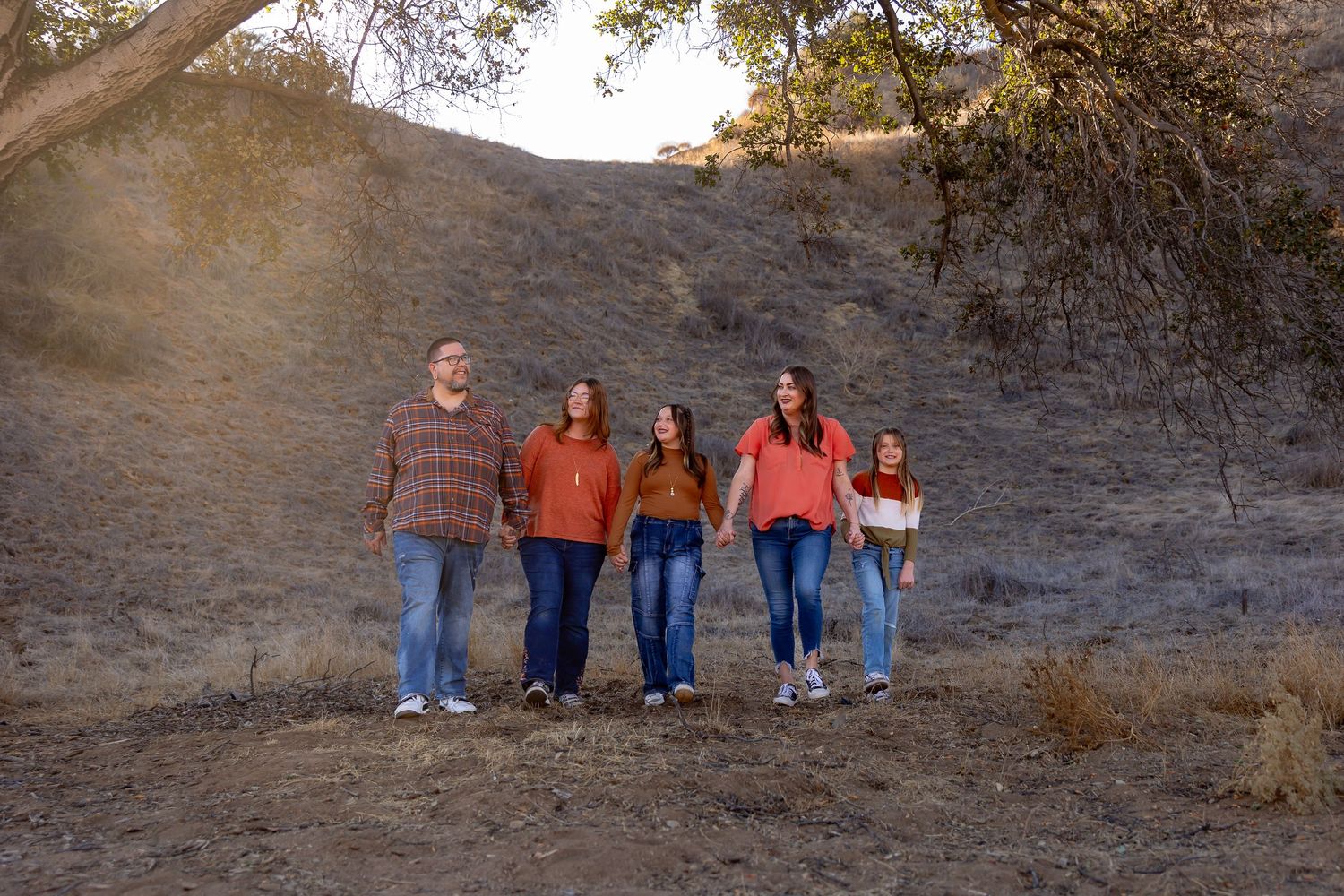 Family group standing together on hillside path during autumn photo session.