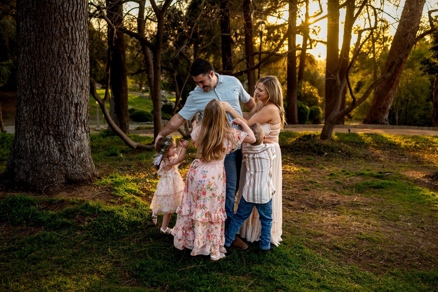 Family embracing outdoors during golden hour in a wooded setting in Redlands.