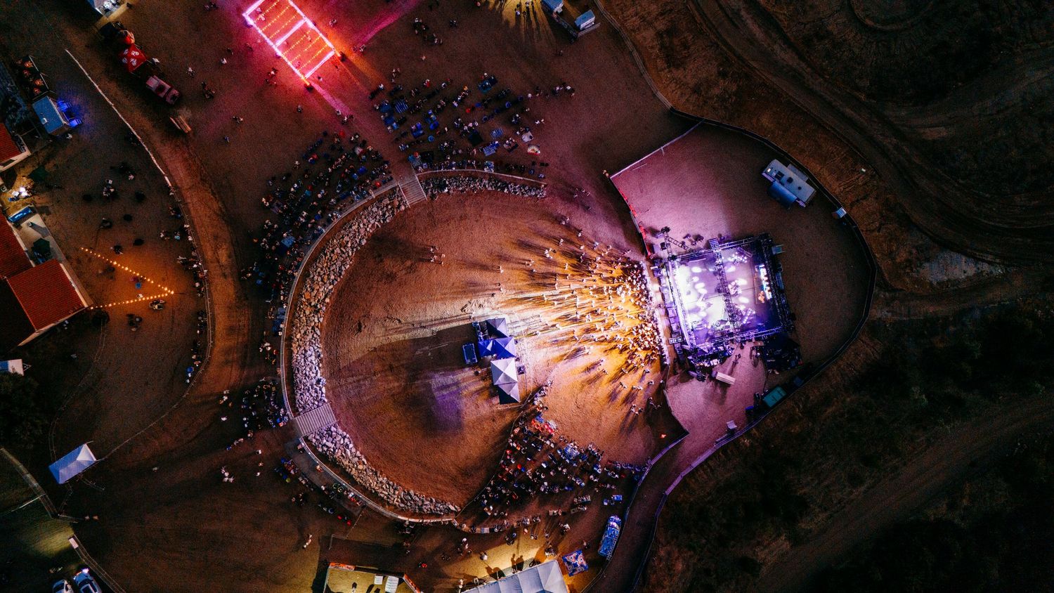 Overhead night shot of circular concert venue with crowd and illuminated stage.