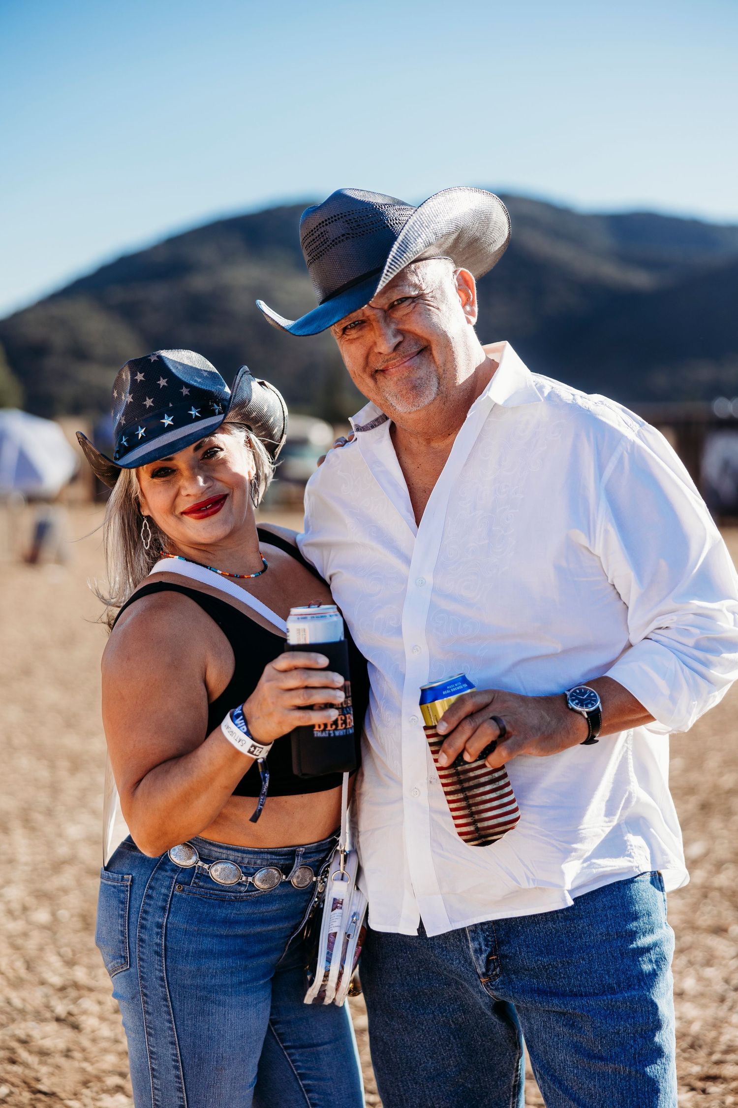 Couple shares candid happy moments together in casual western attire against desert backdrop.