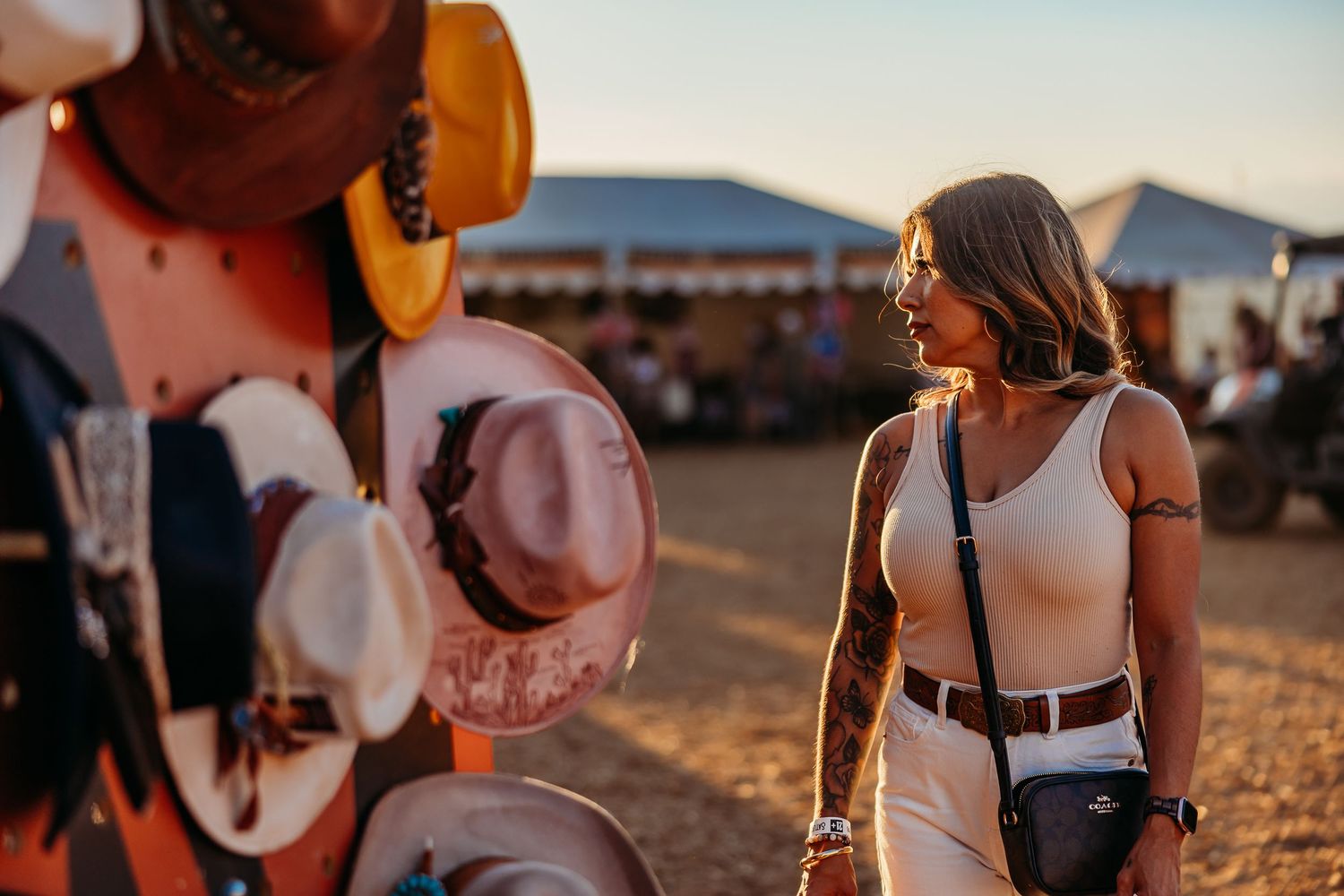 Browsing a hat vendor display at a sunset market with colorful merchandise.