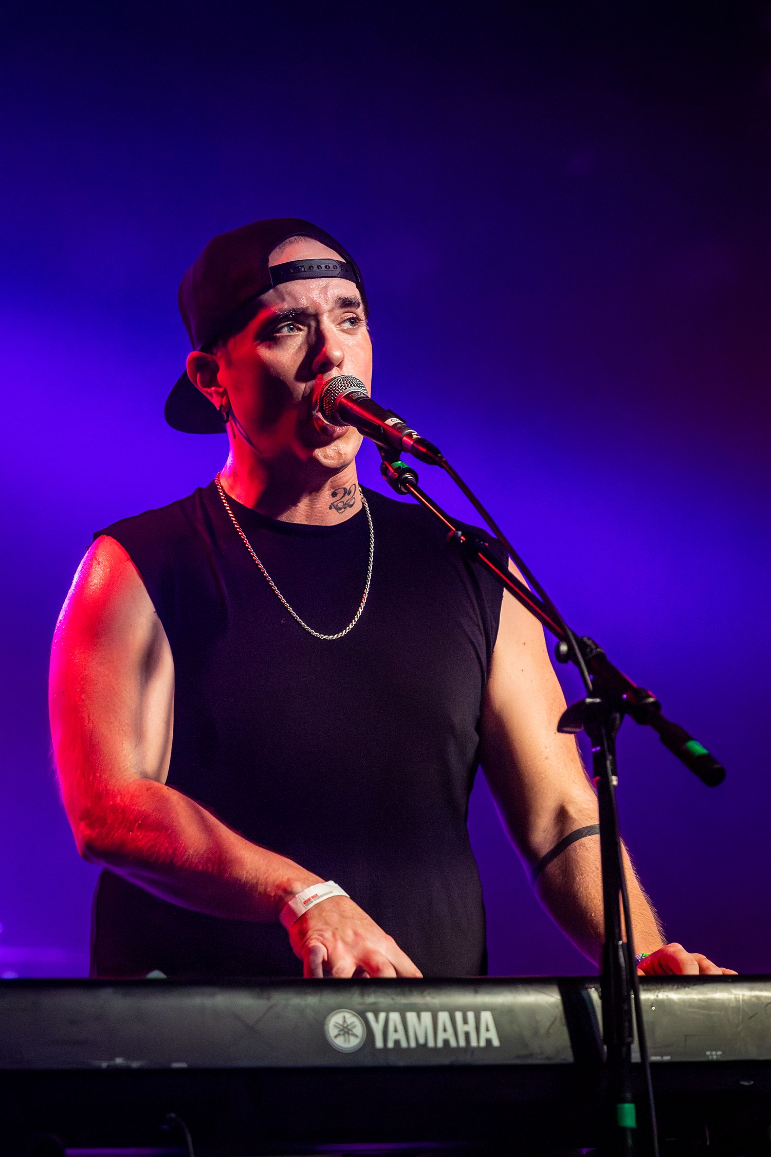 Musician performs on Yamaha keyboard under blue and red stage lighting during live concert in Pomona