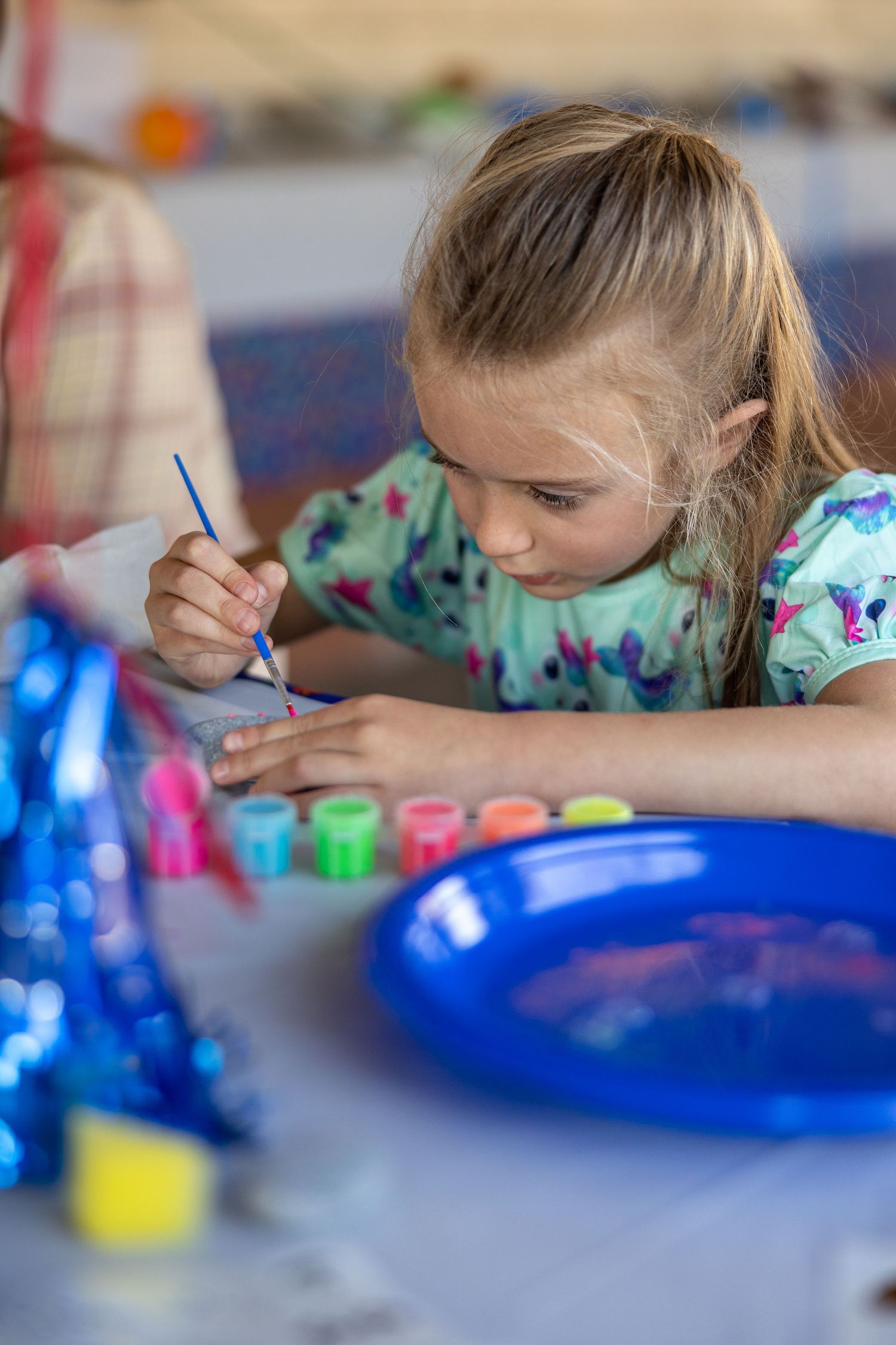 Close-up sequence of art activity with paint and blue plates on gray surface.