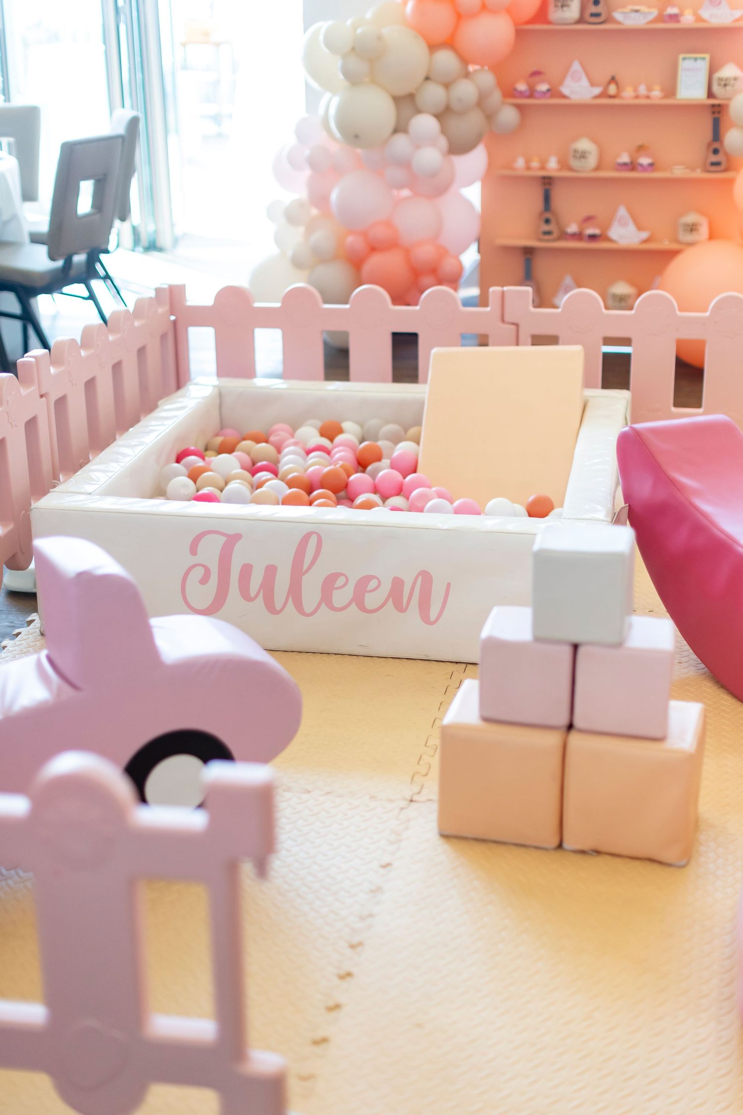 Pink and white decorative blocks spell out 'Juleen' against a coral balloon backdrop in Huntington Beach.